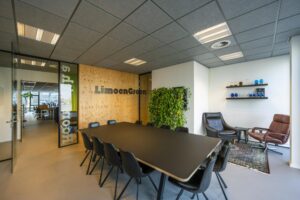 Vergaderruimte van LimoenGroen aan de De Ruijterkade met zwarte tafel, plantenwand en zithoek.
